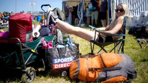 PA Media A festival goer takes a rest on the first day of the Glastonbury Festival at Worthy Farm in Somerset.