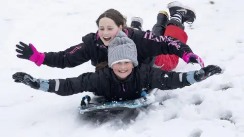 PA Media Two girls on a sled on a golf course near Penicuik, Midlothian