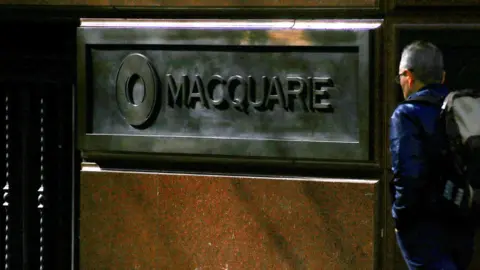 Reuters A pedestrian walks past the logo of Australia's biggest investment bank Macquarie Group Ltd on the outside of their Sydney office headquarters in central Sydney, Australia, July 18, 2017.