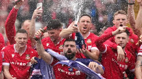 PA Media Wrexham players celebrate after winning promotion