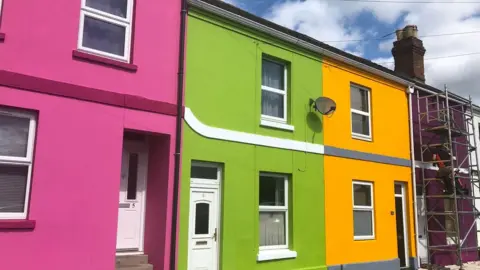 a pink house, green house and yellow house