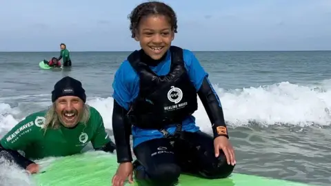 Child on surfboard with surf instructor