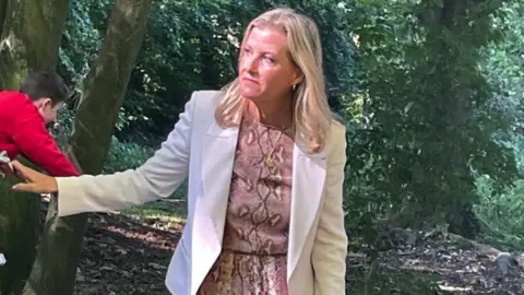 BBC The Duchess of Edinburgh standing in the woods, watching the children take part in outdoor activities