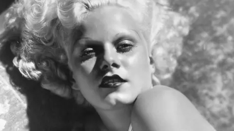 Bettmann via Getty Jean Harlow poses in black and white photograph for 'blonde bombshell' promo shot