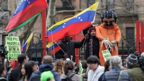 Reuters Protesters demonstrate in support of ousted Venezuelan President Nicolas Maduro, many waving Venezuelan flags and 'Free Maduro' signs. A man also holds up a large stuffed maquette of  Maduro in prison clothes and chains