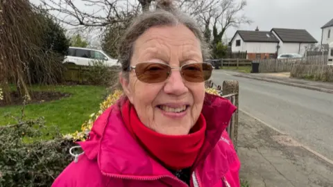 A woman in a pink coat and glasses