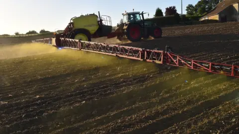 Getty Images Tractor spraying a field