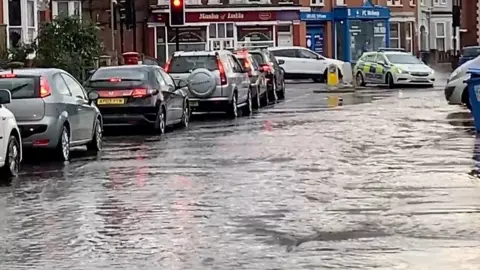 BBC Drains overflowed and manhole covers were lifted along the road near a town centre