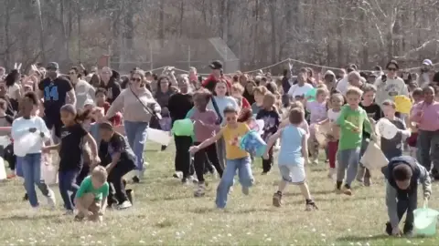 Children run across a grassy field covered in marshmallows