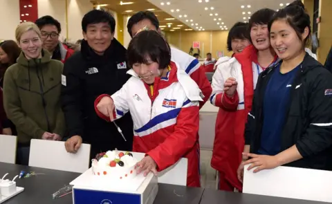 AFP/Getty Images North Korean female ice hockey player Choe Un Gyong (C) cutting a cake while her North and South Korean teammates celebrate