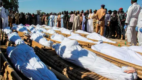 AFP Mourners attend the funeral of 43 farm workers in Zabarmari, about 20km from Maiduguri, Nigeria, on November 29, 2020 after they were killed by Boko Haram fighters in rice fields near the village of Koshobe on November 28, 2020.