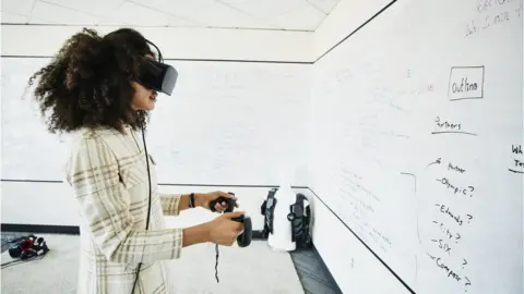 Getty Images Female engineer testing programme on virtual reality headset in computer lab