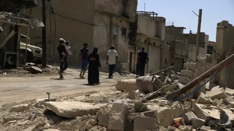 BBC Ishar, a mother-of-four whose husband was killed by IS during the battle for Mosul, walks through the Old City with her children