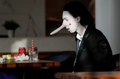 Peter Nicholls / Reuters A person wears a costume at a cafeteria during the pop culture exhibition MCM Comic Con at London's ExCel centre, on 24 October 2021