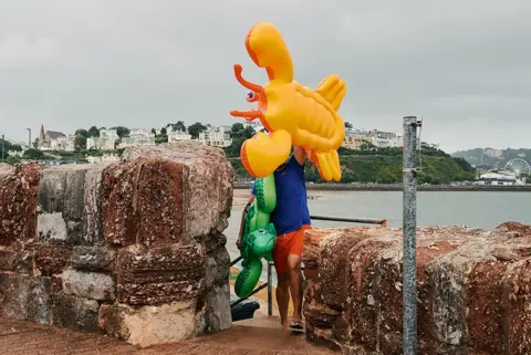 David Hares  A man carries his children's inflatable lilos from the beach