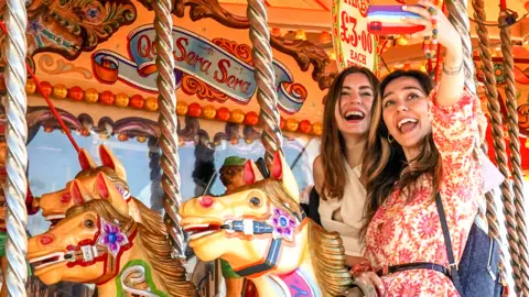 Getty Images Two visitors pose on a carousel in Brighton, England, on 31 May 2021