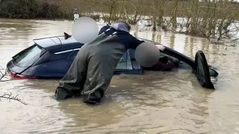 A stranded driver is helped from his car.