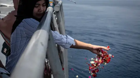 Getty Images A family of one of the victims of Lion Air flight JT 610 throws flowers on deck of the Indonesian Navy ship, 6 November 2018