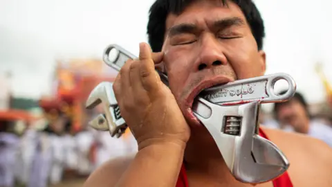 AFP A devotee with two wrenches pierced through his cheek