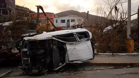 Paul Blake/BBC Debris and an overturned car on British Virgin islands