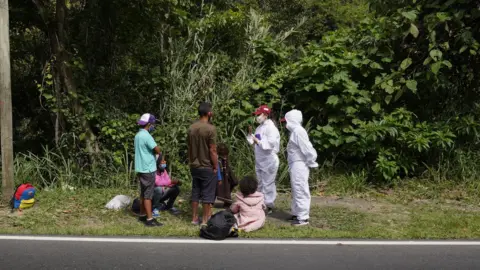 Workers from humanitarian group Consornoc approach migrants outside Pamplona and give them information on the road ahead.
