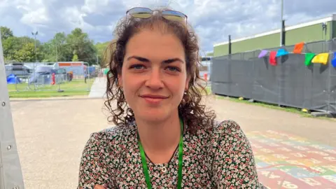 Nic Rigby/BBC Emily Fraser smiling, wearing a flowery dress