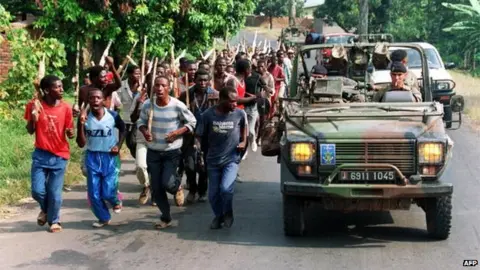 AFP French troops driving past Hutu militiamen