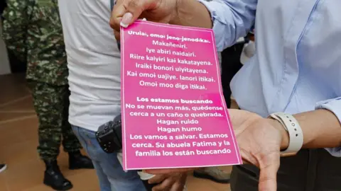 EPA A person shows a poster in the Uitoto language, native to the Mukutuy children, and in Spanish, with a message about the minors lost for 20 days after a plane crash in southern Colombia, prior to a group of soldiers going to to the search area, from the Twenty-second Jungle Brigade in San Jose del Guaviare, Colombia, 20 May 2023.