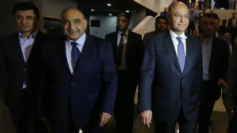 AFP Iraq's Prime Minister-designate Adel Abdul Mahdi (2nd Left) and Barham Saleh (2nd Right) walk out of the Iraqi parliament on 2 October 2018