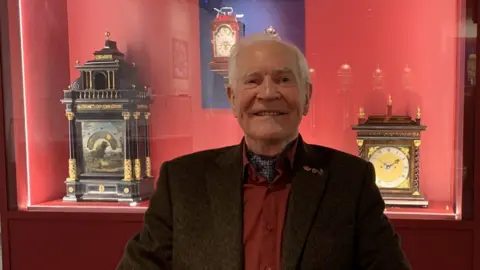 Dr John Taylor in front of a case in the exhibition