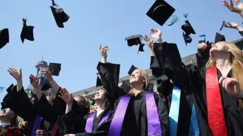 Getty Images Students graduating and throwing hats into the air