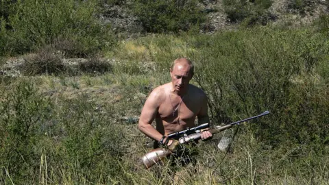 AFP/Getty Putin carrying a sniper rifle while hunting topless