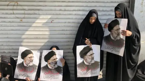 EPA Iranians hold portraits of late president Ebrahim Raisi as they mourn during a funeral processions ceremony in Tehran, Iran, 22 May 2024.