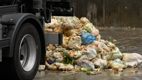 A pile of food waste in a recycling depot. The back wheel of a lorry is also in the photograph
