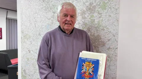 A man standing proudly holding his programme from the final