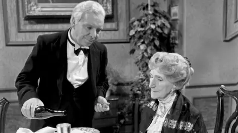 Alamy A black and white still from Dinner for one shows James the butler pour drinks for Miss Sophie