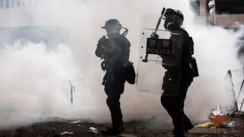 AFP/Getty Images Police officers surrounded by tear gas during a rally by protesters against a controversial extradition law proposal, in Hong Kong on 12 June 2019