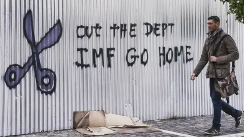 Getty Images A citizen passes by graffiti against the IMF on February 10, 2015 in Athens, Greece