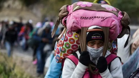 AFP A Venezuelan migrant woman heading to Peru carries bags as she walks along the Panamerican highway in Tulcan, Ecuador, after crossing from Colombia, on August 21, 2018