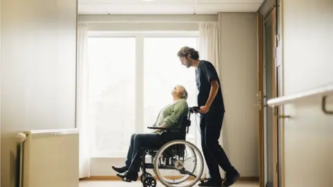 Getty Images Carer and person in wheelchair