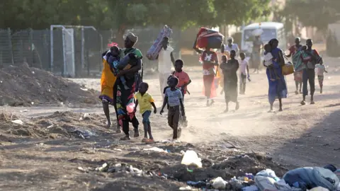 Getty Images People flee their neighbourhoods amid fighting between the army and paramilitaries in Khartoum, 19 April 2023