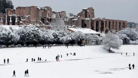 Reuters People walk during a heavy snowfall at the Circus Maximus in Rome