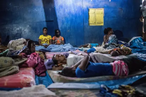Olivia Acland Women and children sleep on the floor of a church built from corrugated iron