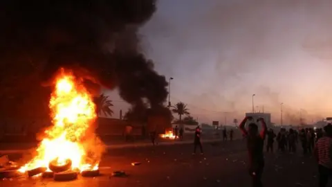 AFP/Getty Images People protest near burning tyres in Baghdad, Iraq. Photo: 5 October 2019