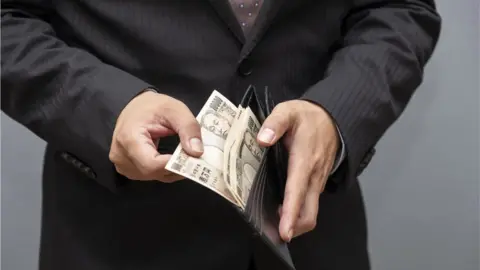 Getty Images Hands holding Japanese yen