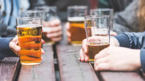 Getty Images Half empty pints of lager on wooden table