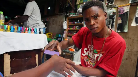 Reuters A nail artist fixes client's nail on Valentine's Day at Wuse market in Abuja, Nigeria 14 February 2018