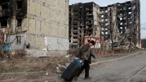 Reuters A man walks past a destroyed building in Mariupol