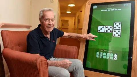 Down Hall Down Hall resident Stanley playing dominoes on a giant tablet.