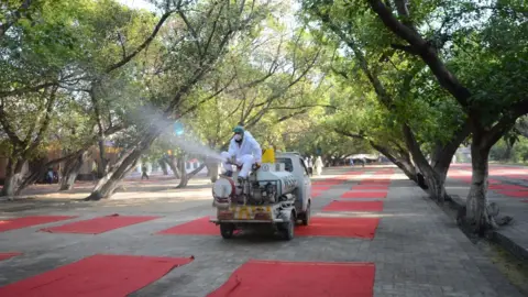 Getty Images Workers disinfect the area where muslims offer the Eid al Fitr prayer in Peshawar